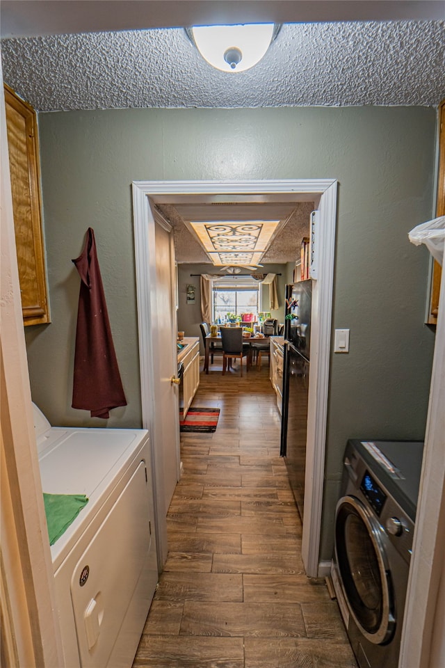 clothes washing area featuring hardwood / wood-style floors, cabinets, and washer and clothes dryer