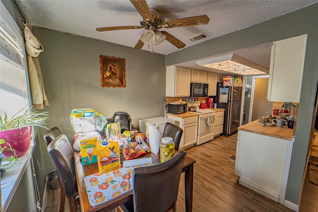 dining area with ceiling fan, light wood-type flooring, and a textured ceiling