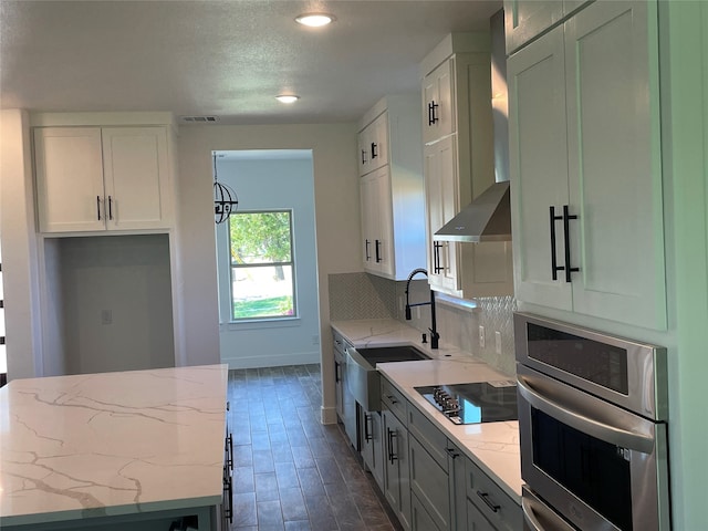 kitchen featuring stainless steel oven, black electric cooktop, white cabinets, and light stone countertops