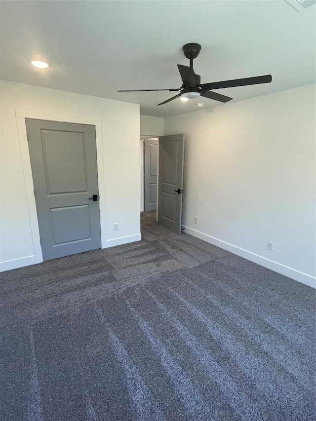 unfurnished bedroom with ceiling fan and dark colored carpet