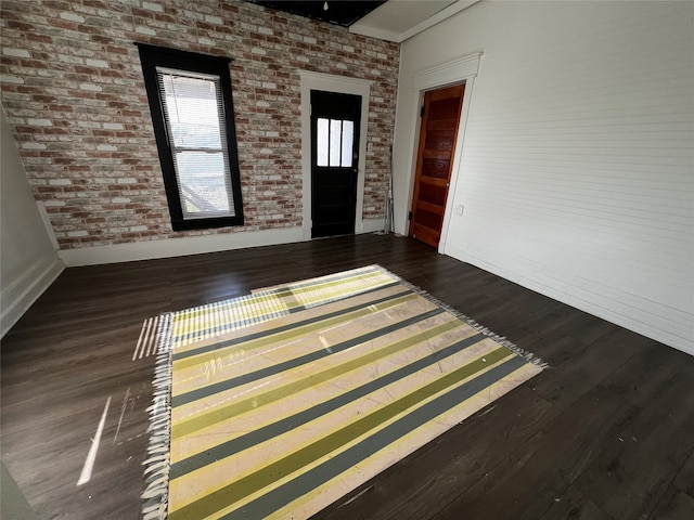 interior space with brick wall and dark hardwood / wood-style flooring