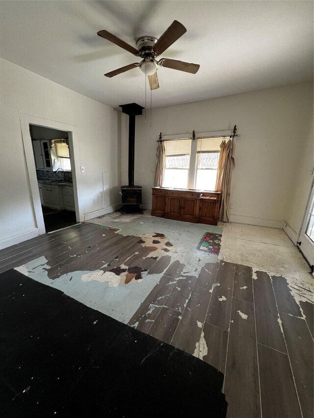 interior space with a wood stove, hardwood / wood-style flooring, and ceiling fan