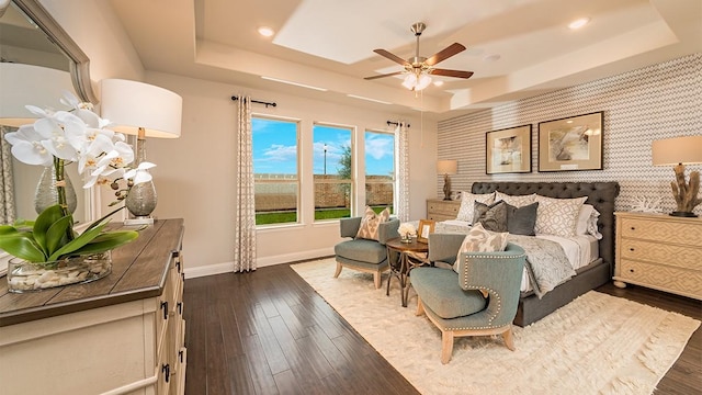 bedroom featuring ceiling fan, dark wood-type flooring, and a raised ceiling