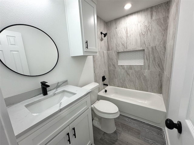 full bathroom with hardwood / wood-style flooring, tiled shower / bath combo, vanity, and toilet