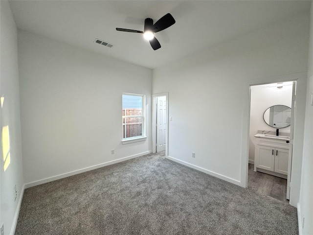 unfurnished bedroom featuring ceiling fan, ensuite bath, sink, and dark carpet