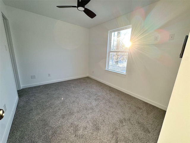 empty room with ceiling fan and dark carpet