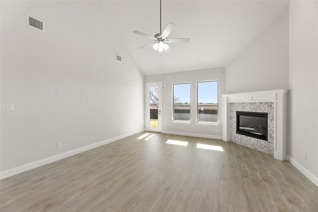 unfurnished living room featuring a tile fireplace, light hardwood / wood-style flooring, high vaulted ceiling, and ceiling fan