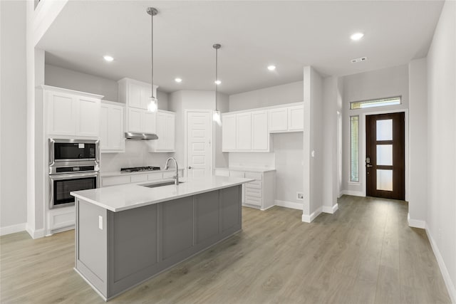 kitchen with sink, a center island with sink, white cabinets, and appliances with stainless steel finishes