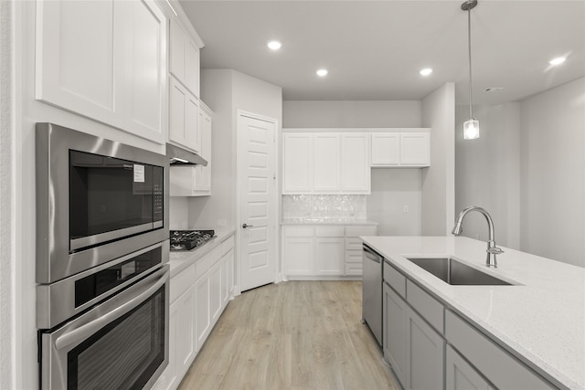 kitchen with white cabinetry, sink, light stone counters, pendant lighting, and appliances with stainless steel finishes