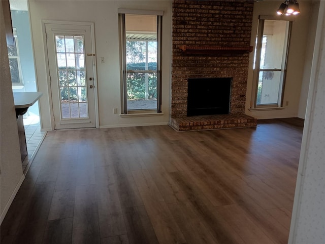 unfurnished living room featuring dark hardwood / wood-style flooring and a brick fireplace