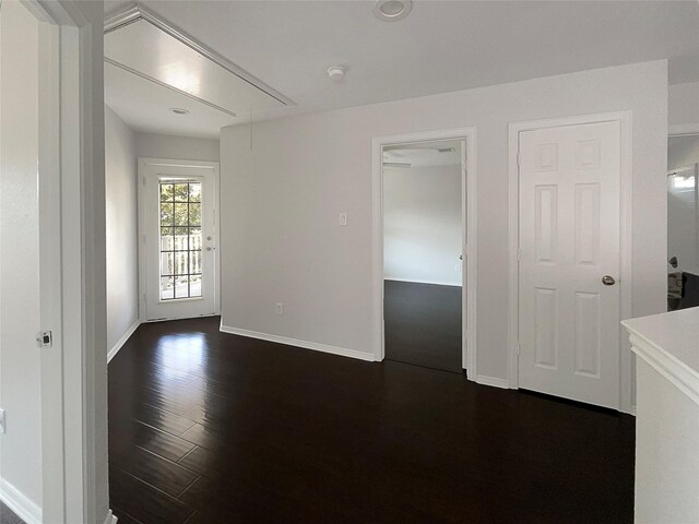 empty room with attic access, baseboards, and dark wood-style flooring