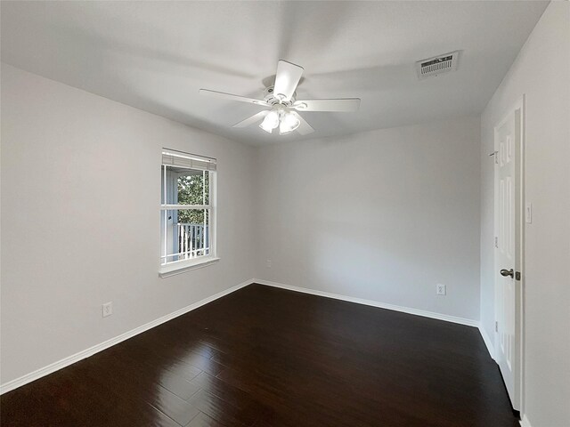 empty room featuring dark wood-type flooring, visible vents, baseboards, and ceiling fan