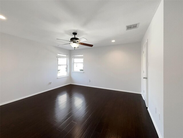 empty room with visible vents, a ceiling fan, baseboards, and dark wood-style flooring