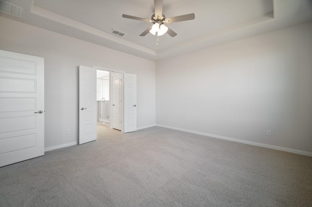 unfurnished bedroom with carpet floors, a raised ceiling, visible vents, and baseboards