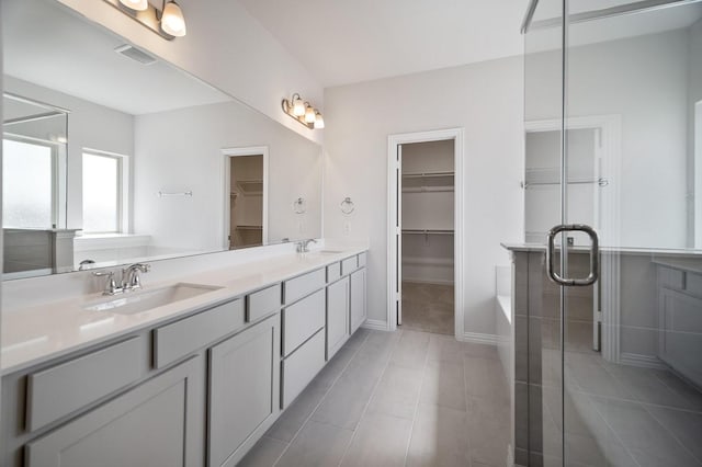 full bathroom with double vanity, visible vents, a walk in closet, and a sink