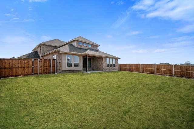 back of house with brick siding, a fenced backyard, and a yard