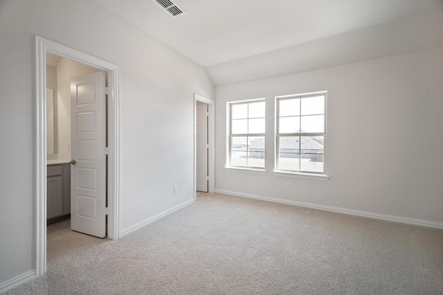 unfurnished room featuring light carpet, baseboards, visible vents, and lofted ceiling