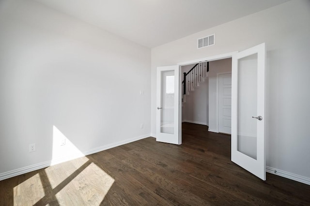 unfurnished bedroom with french doors, dark wood-type flooring, visible vents, and baseboards