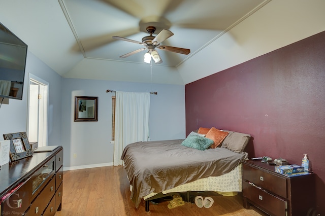 bedroom featuring crown molding, vaulted ceiling, light wood-type flooring, and ceiling fan