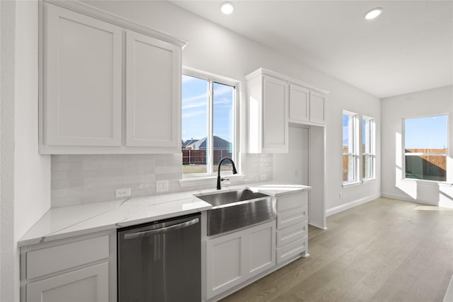 kitchen with light stone countertops, decorative backsplash, white cabinetry, and stainless steel dishwasher