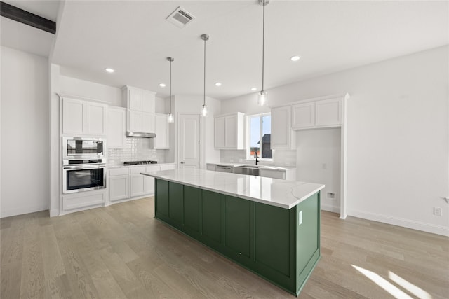 kitchen with appliances with stainless steel finishes, a center island, white cabinetry, and pendant lighting