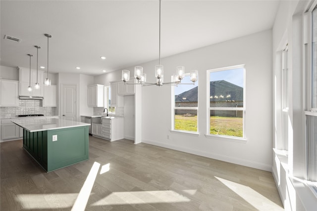 kitchen with white cabinets, decorative light fixtures, a center island, and tasteful backsplash