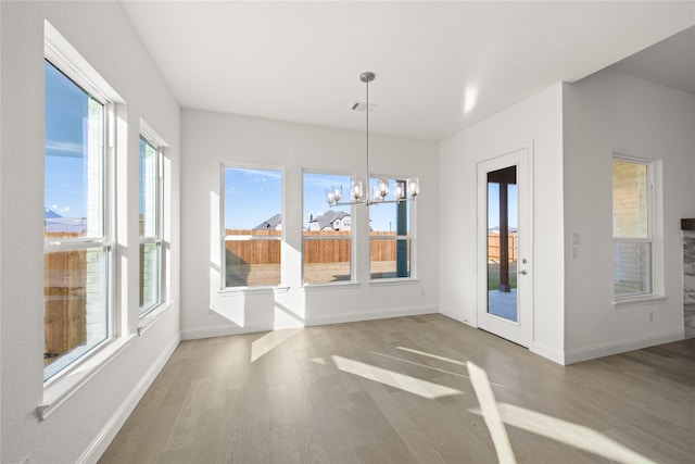 unfurnished dining area with an inviting chandelier and hardwood / wood-style flooring