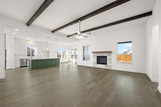 unfurnished living room featuring a fireplace, beamed ceiling, ceiling fan, and dark wood-type flooring