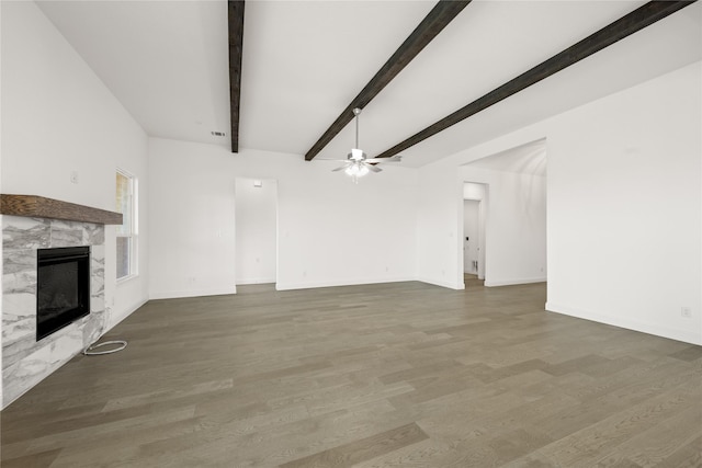 unfurnished living room featuring beam ceiling, a premium fireplace, hardwood / wood-style floors, and ceiling fan