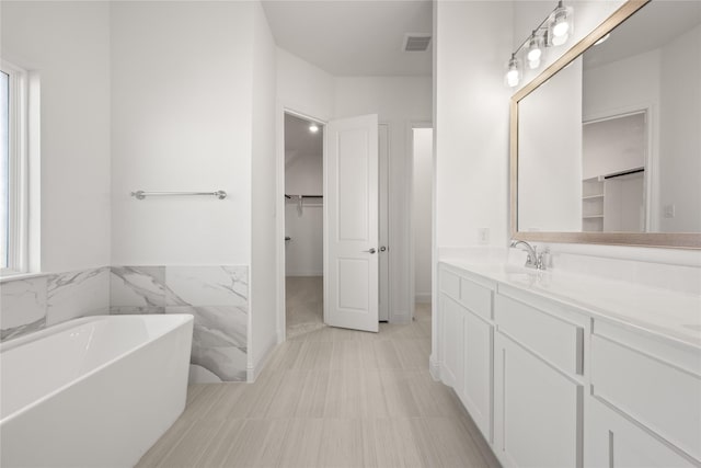 bathroom featuring tile patterned floors, vanity, a bath, and tile walls