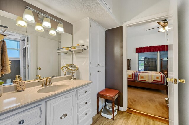 bathroom featuring wood-type flooring, vanity, a textured ceiling, and ceiling fan