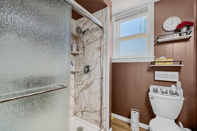 bathroom featuring hardwood / wood-style floors, wooden walls, a shower with shower door, and toilet