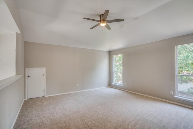 empty room with lofted ceiling, plenty of natural light, light colored carpet, and ceiling fan