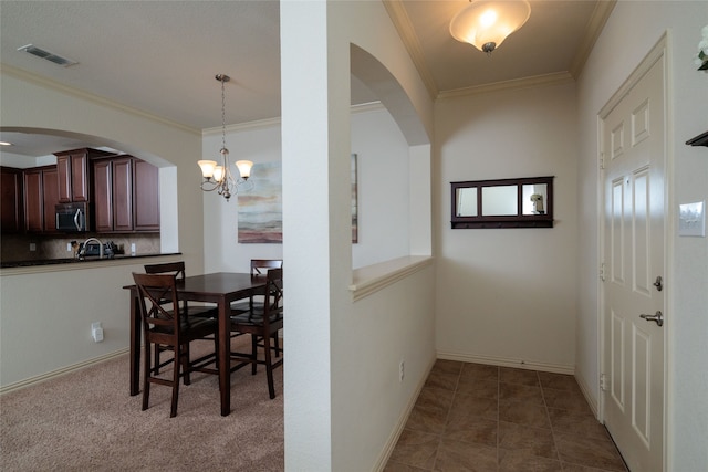 dining room with carpet flooring, a notable chandelier, and ornamental molding