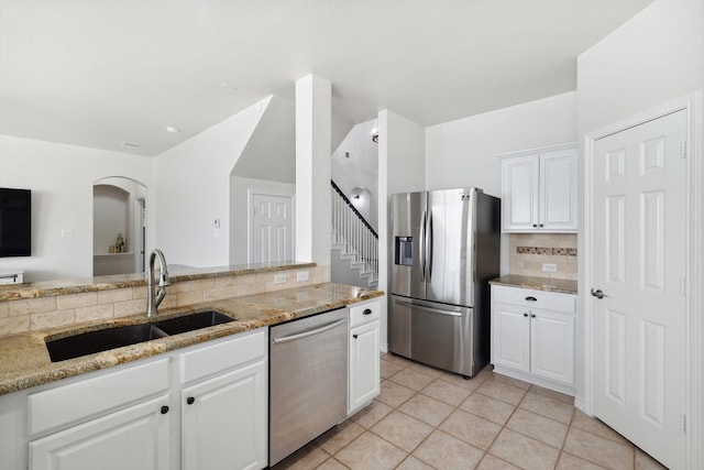 kitchen featuring light stone counters, decorative backsplash, sink, white cabinetry, and appliances with stainless steel finishes