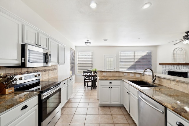 kitchen with appliances with stainless steel finishes, white cabinetry, sink, and light tile patterned floors