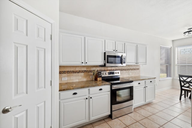 kitchen with white cabinets, stainless steel appliances, backsplash, and light tile patterned floors