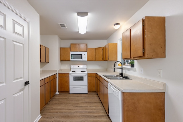 kitchen with light hardwood / wood-style flooring, white appliances, and sink