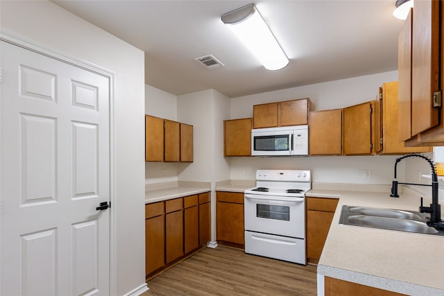 kitchen with sink, wood-type flooring, and white appliances