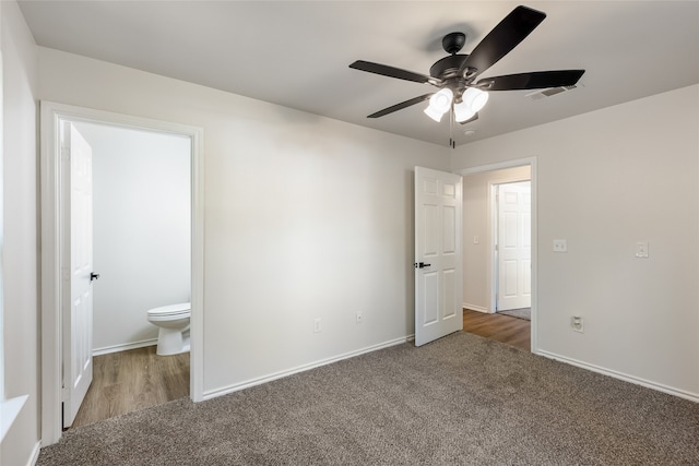 unfurnished bedroom featuring dark colored carpet, connected bathroom, and ceiling fan