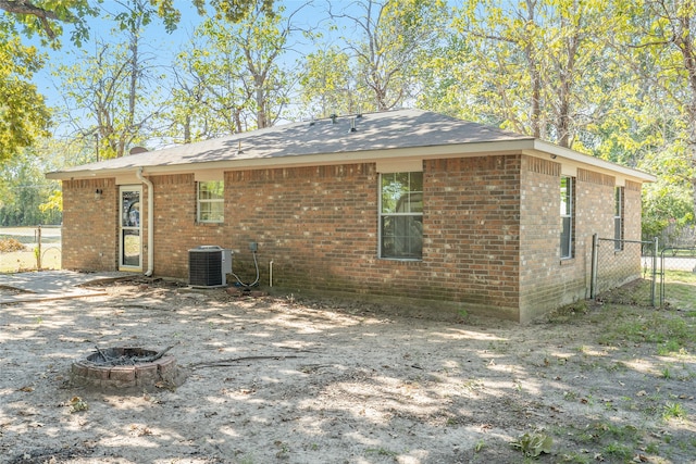 back of property featuring central air condition unit and an outdoor fire pit