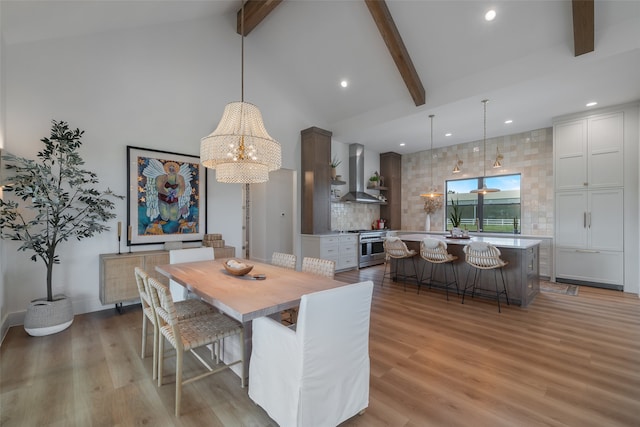 dining area featuring a notable chandelier, beam ceiling, light wood-type flooring, and high vaulted ceiling