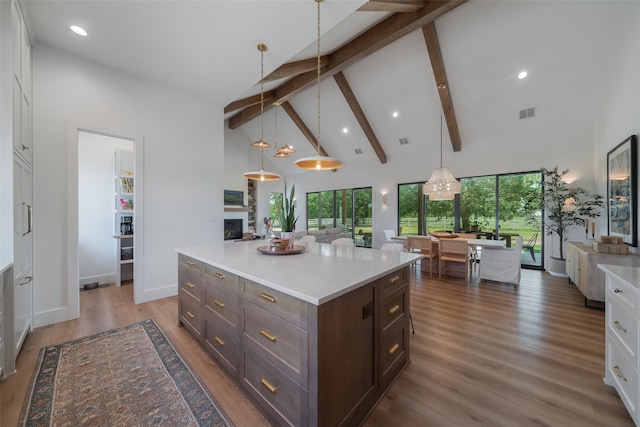 kitchen with pendant lighting, white cabinetry, dark wood-type flooring, and high vaulted ceiling