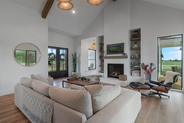 living room featuring beamed ceiling, french doors, light wood-type flooring, and high vaulted ceiling