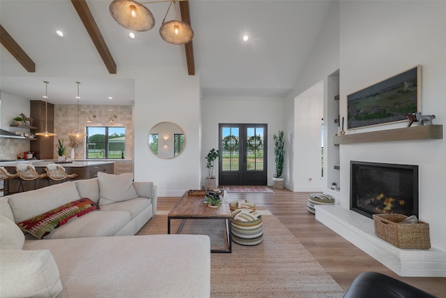 living room featuring vaulted ceiling with beams, french doors, sink, and light hardwood / wood-style flooring