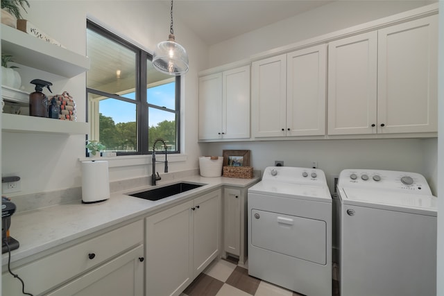 clothes washing area with washer and clothes dryer, cabinets, and sink