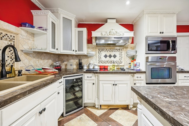 kitchen featuring stainless steel appliances, backsplash, wine cooler, sink, and white cabinetry