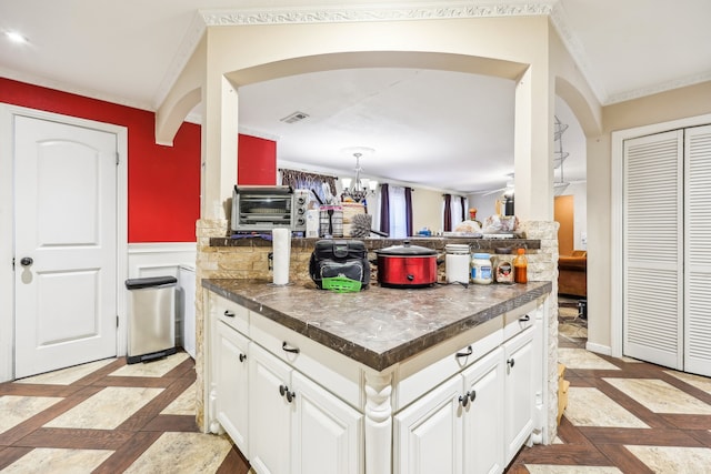 kitchen featuring crown molding, white cabinetry, and an inviting chandelier