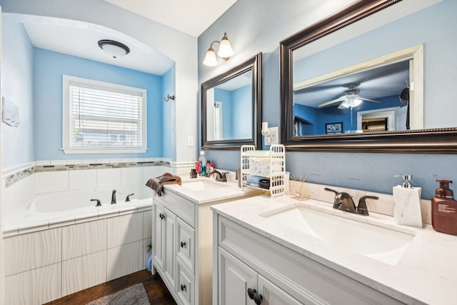 bathroom featuring vanity, hardwood / wood-style floors, tiled tub, and ceiling fan