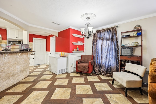 living area with an inviting chandelier and crown molding